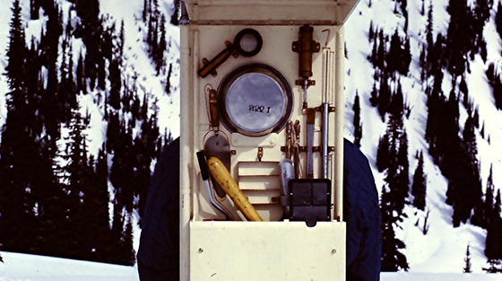 Color photo of avalanche researcher carrying tool kit on his back